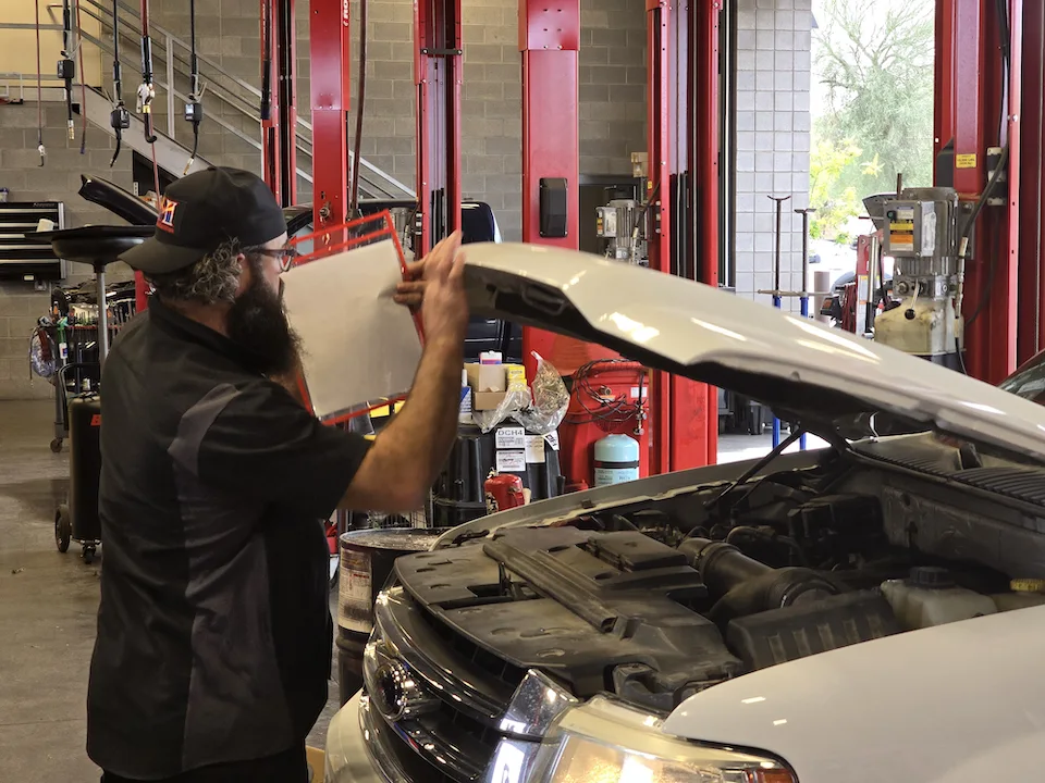 bearded mechanic closing hood on white ford truck